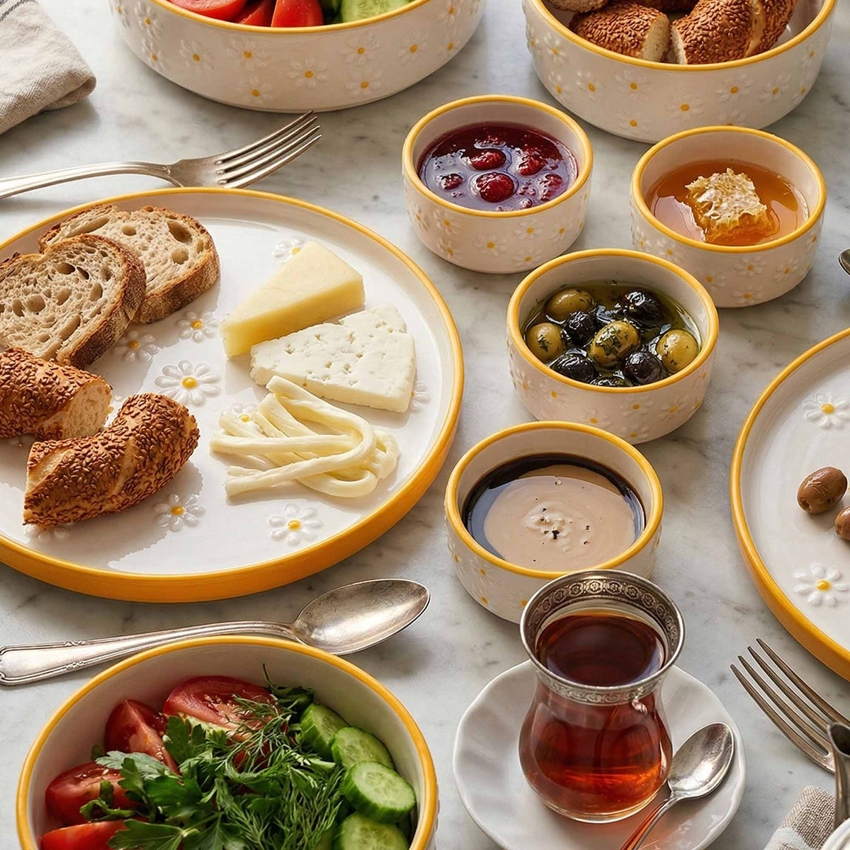 Assorted food items including bread, cheese, olives, and a cup of tea on a marble surface.