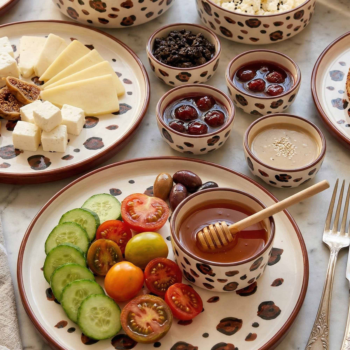 Plated appetizer with sliced vegetables, olives, and a bowl of dip on a marble surface.