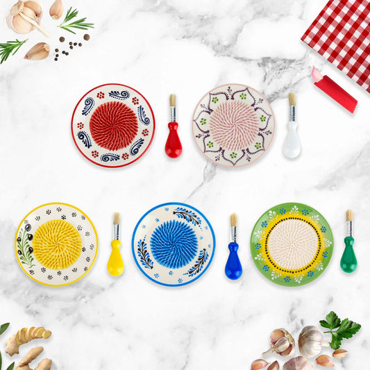 Colorful ceramic garlic grater plates with decorative patterns on a marble surface.