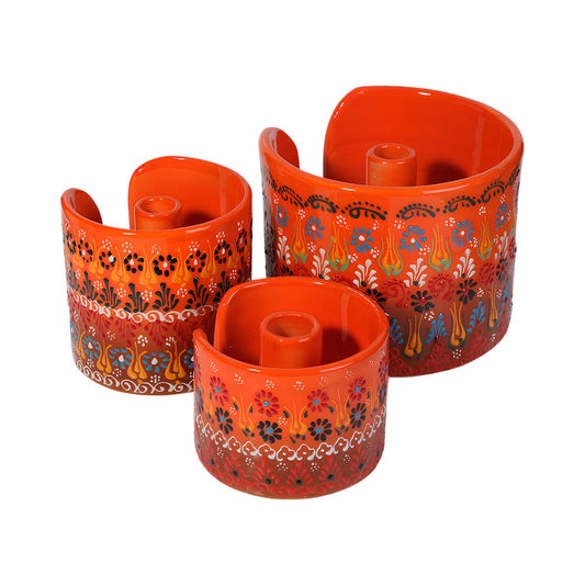 Three orange ceramic paper towel holders with floral patterns on a white background