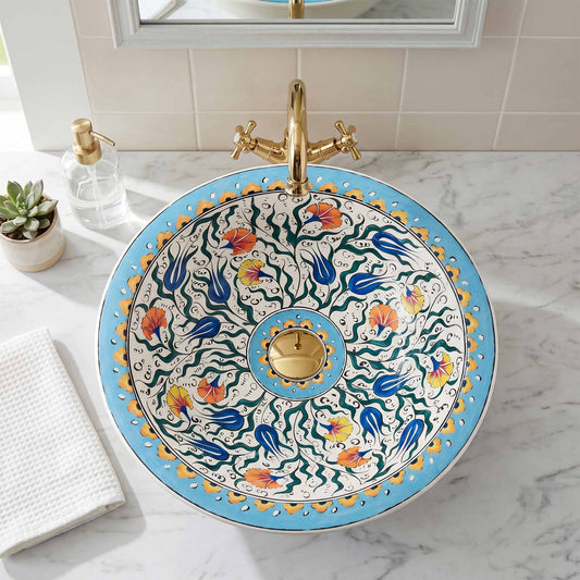 Decorative sink with floral patterns and gold accents on a marble countertop.