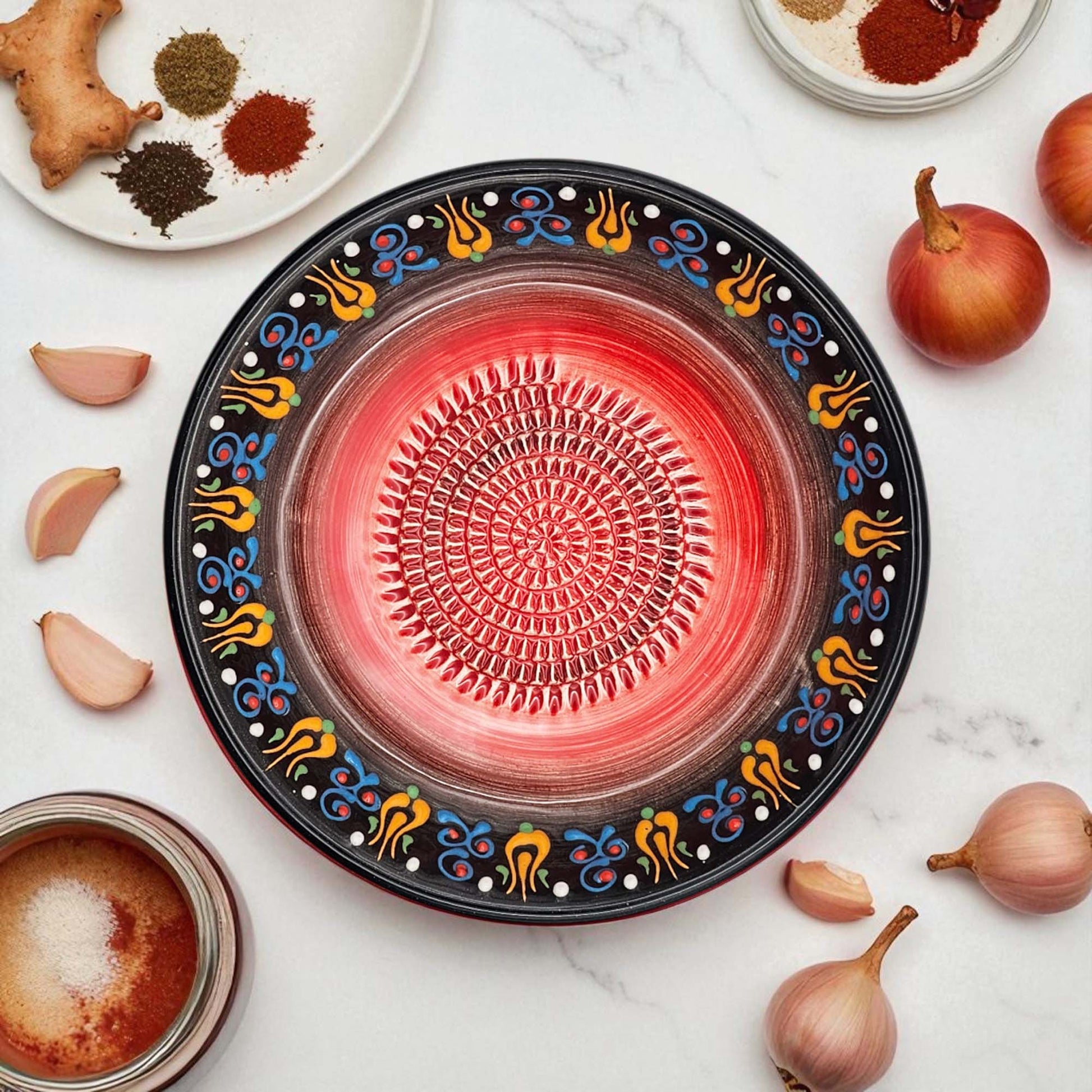 Decorative garlic grater bowl with colorful a white surface with ingredients.