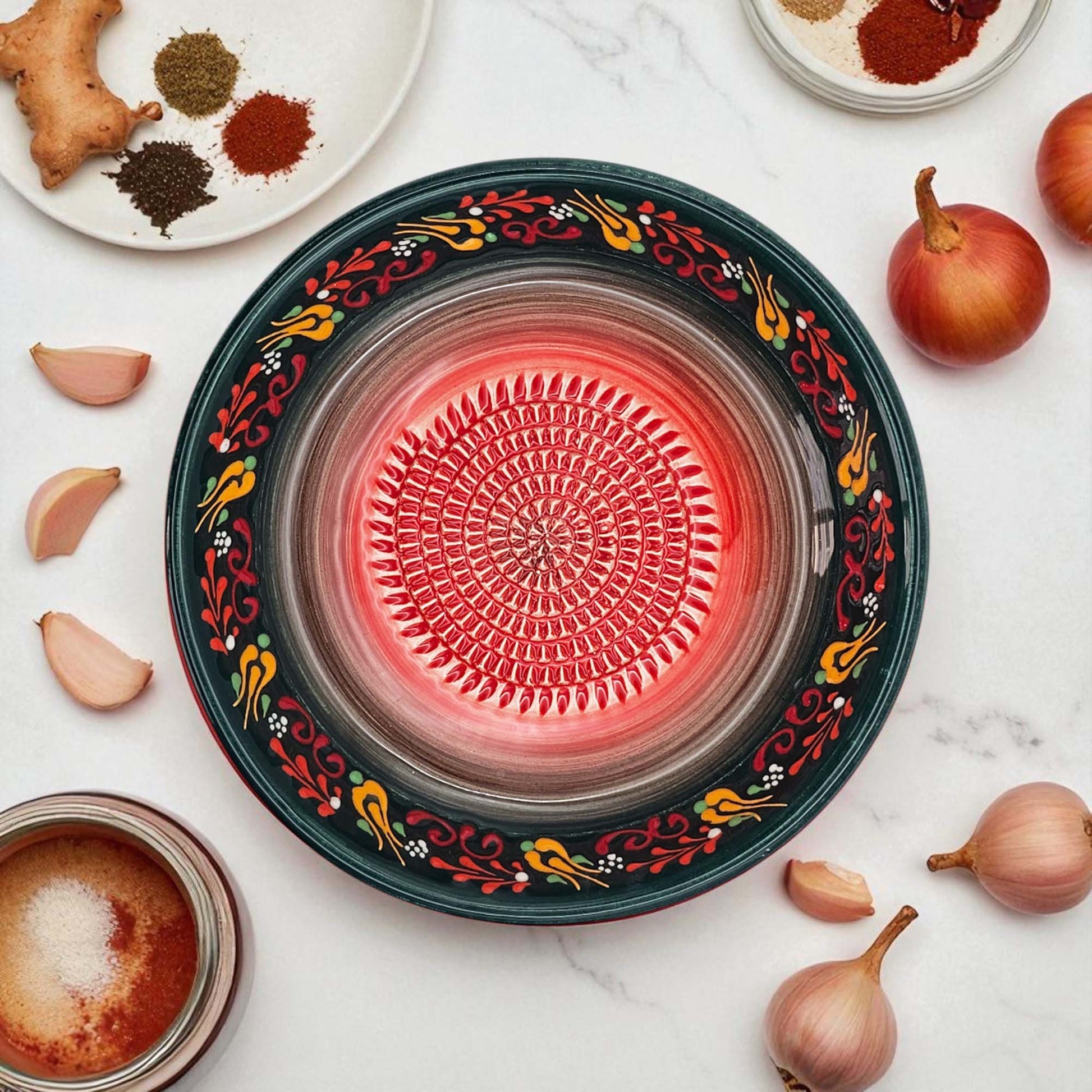 Decorative garlic grater bowl with colorful patterns on a white surface with ingredients.