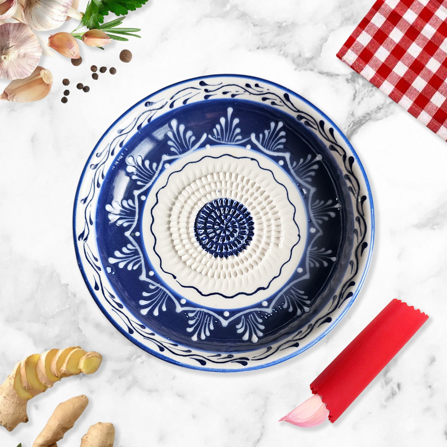 Decorative blue and white ceramic garlic grater bowl on a marble surface with kitchen items around