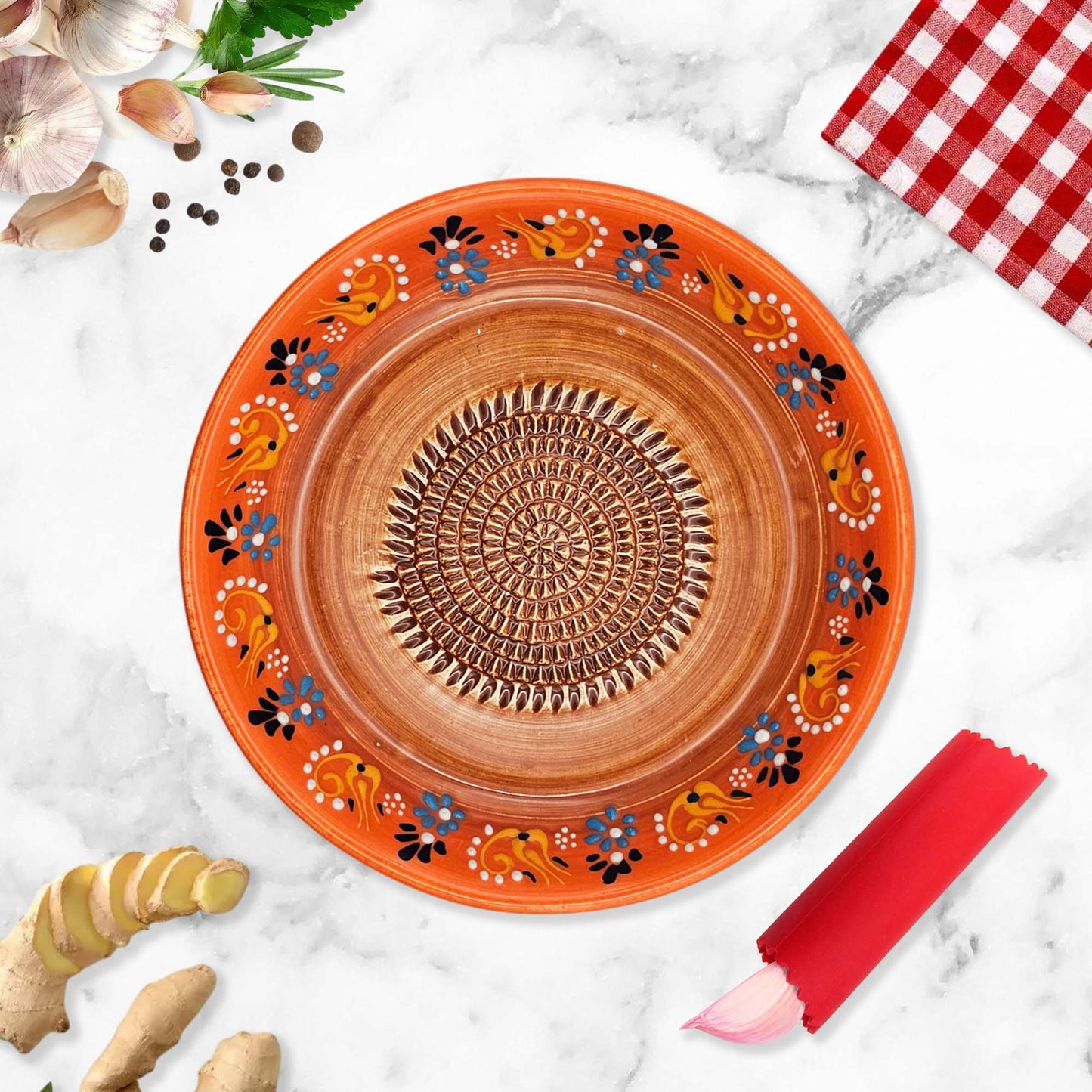Decorative ceramic garlic grater bowl with floral patterns on a marble surface with kitchen items.