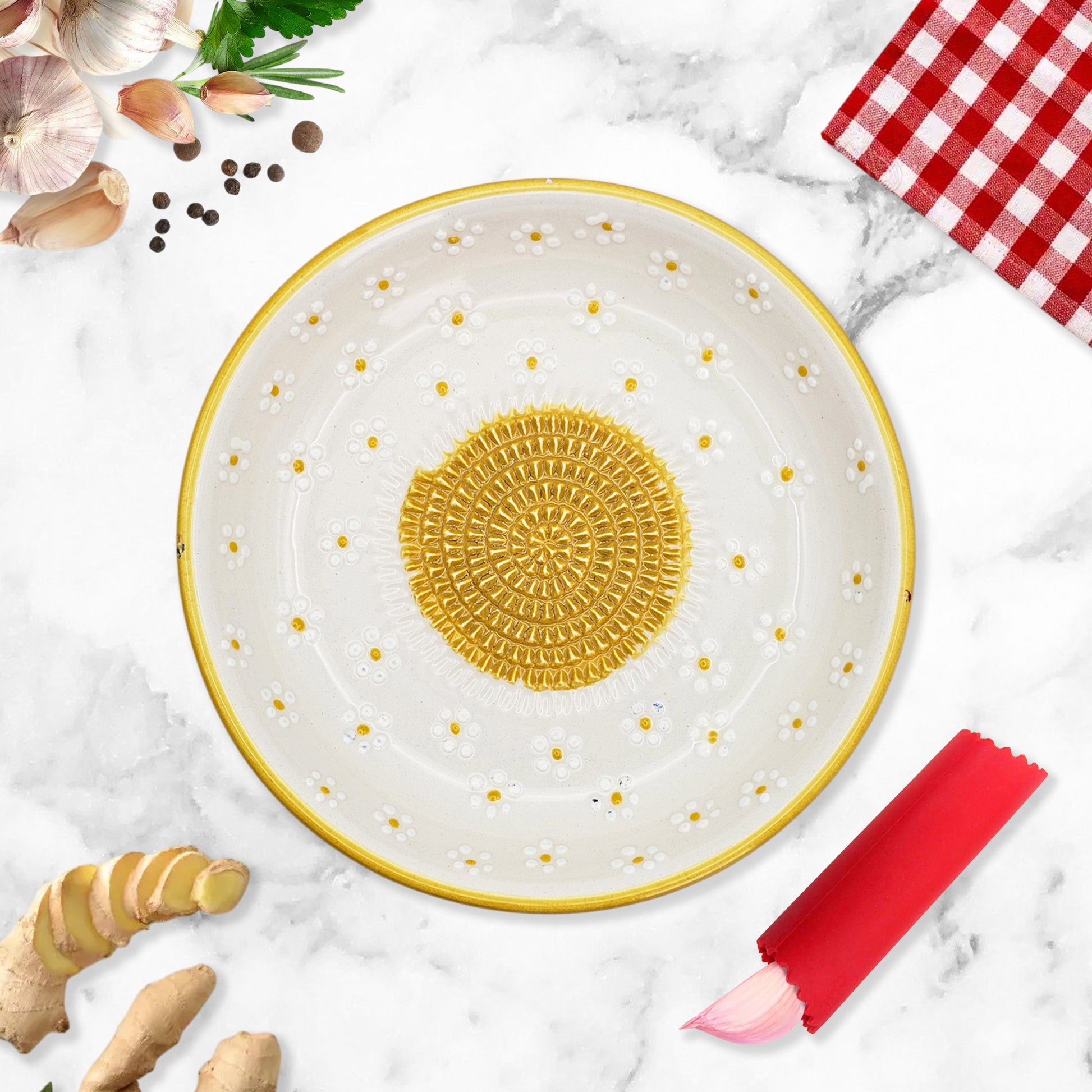 Decorative ceramic garlic grater bowl with gold accents on a marble surface with kitchen items.