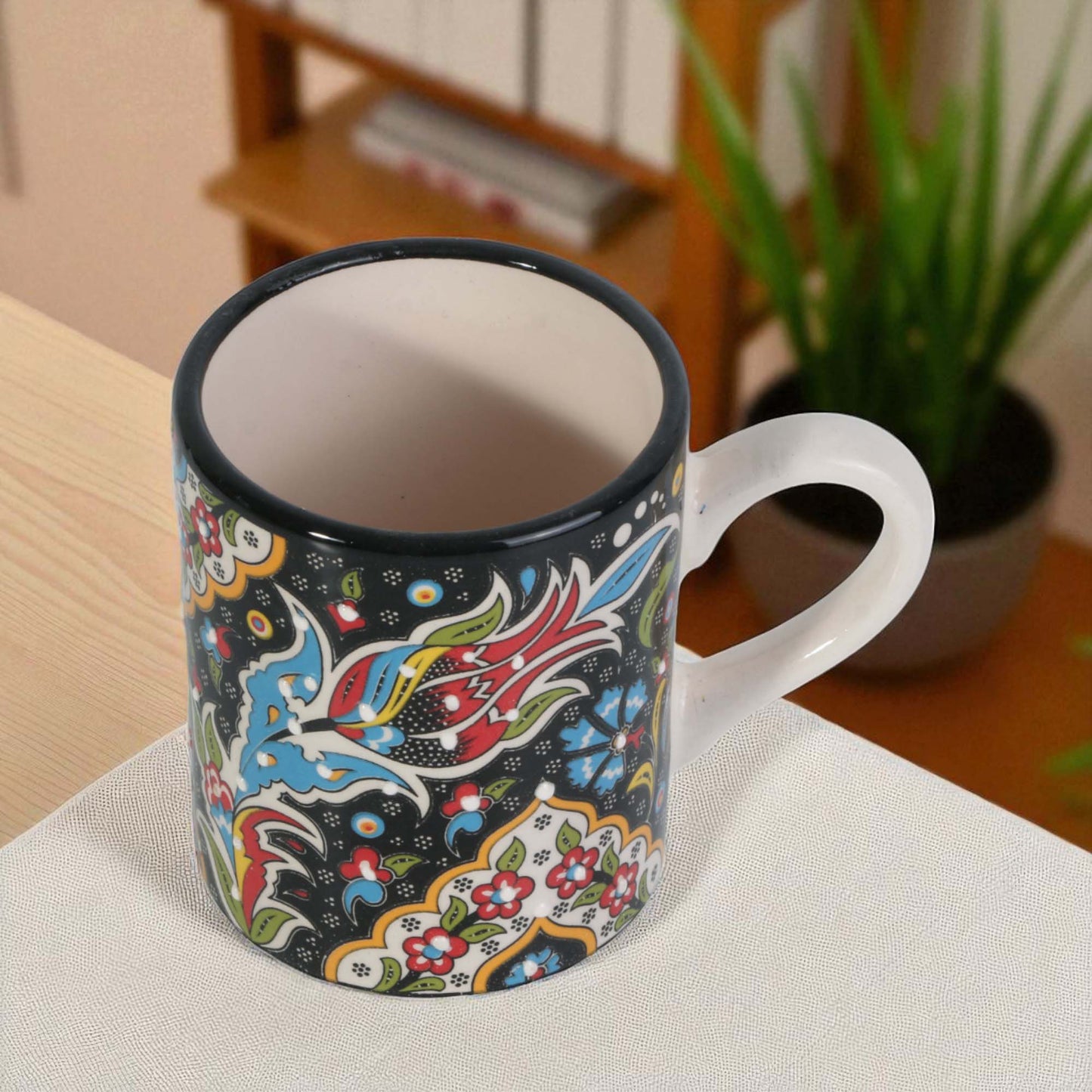 Colorful coffee mug with floral and abstract designs on a white surface.