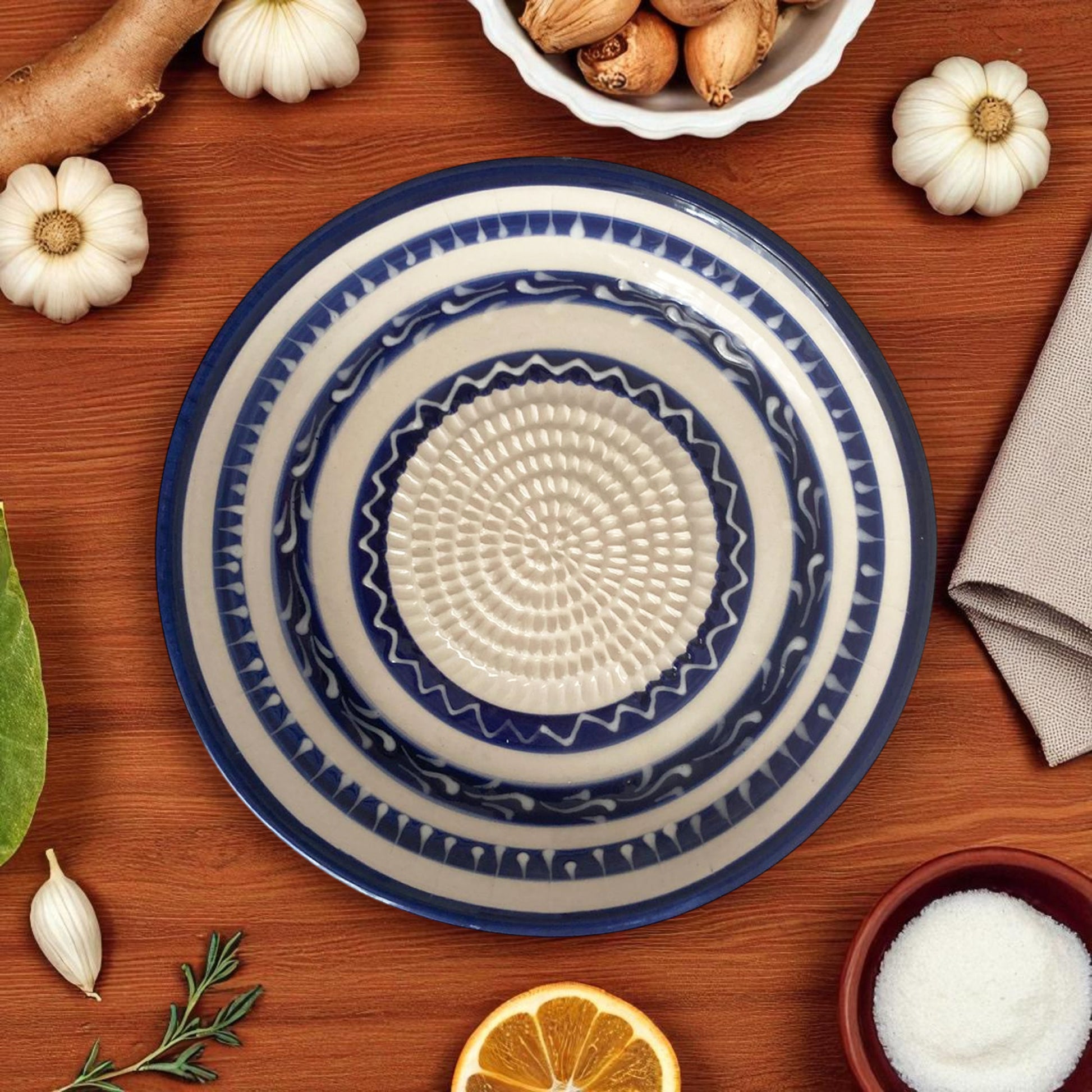 Decorative blue and white garlic grater bowl on a wooden surface with pumpkins and other items.