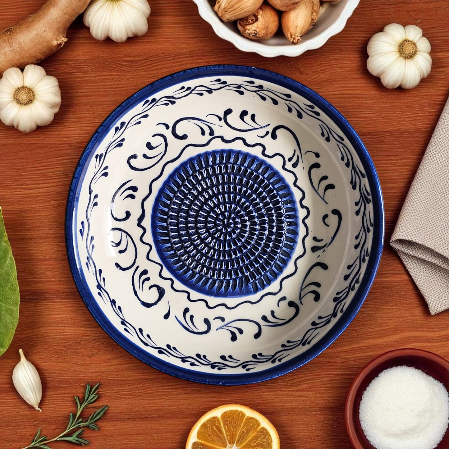 Decorative ceramic garlic grater bowl with blue and white patterns on a wooden surface with pumpkins and a napkin.
