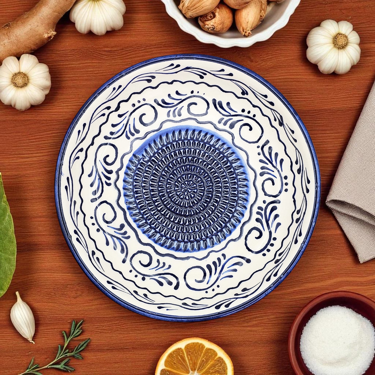 Decorative ceramic garlic grater bowl with blue and white patterns on a wooden surface with autumnal elements.