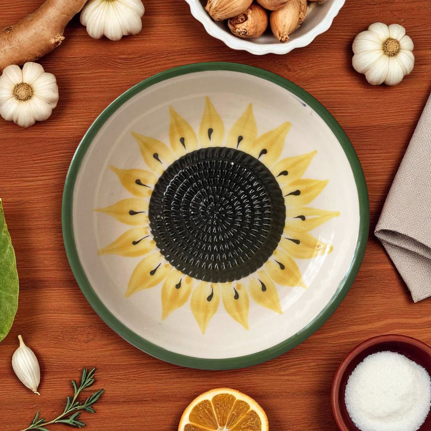 Ceramic garlic grater bowl with sunflower design on a wooden table with decorative items.