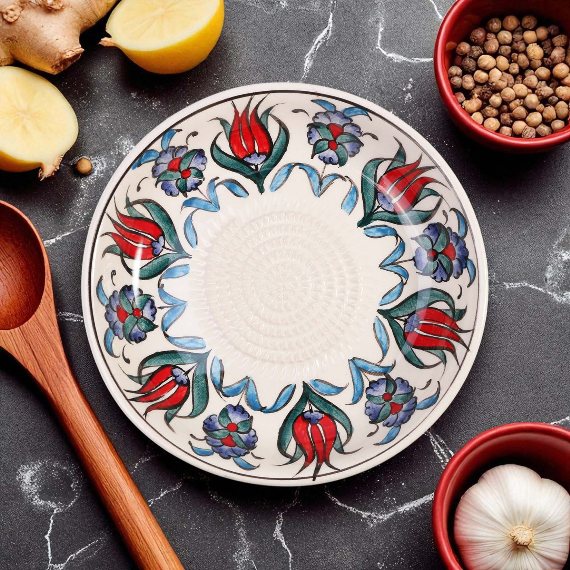 Decorative ceramic garlic grater bowl with floral patterns on a kitchen counter with ingredients.
