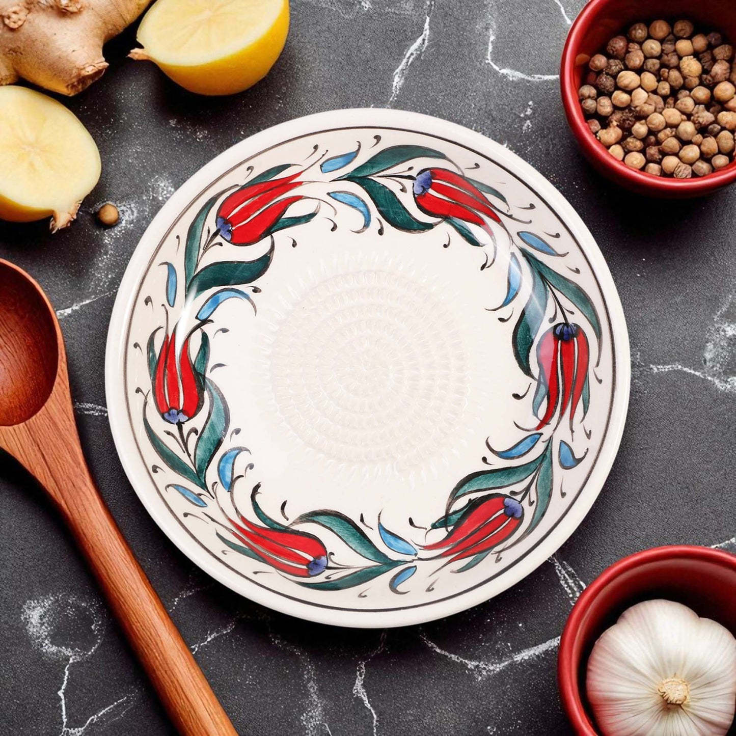 Decorative ceramic garlic grater bowl with floral design on a kitchen counter with ingredients