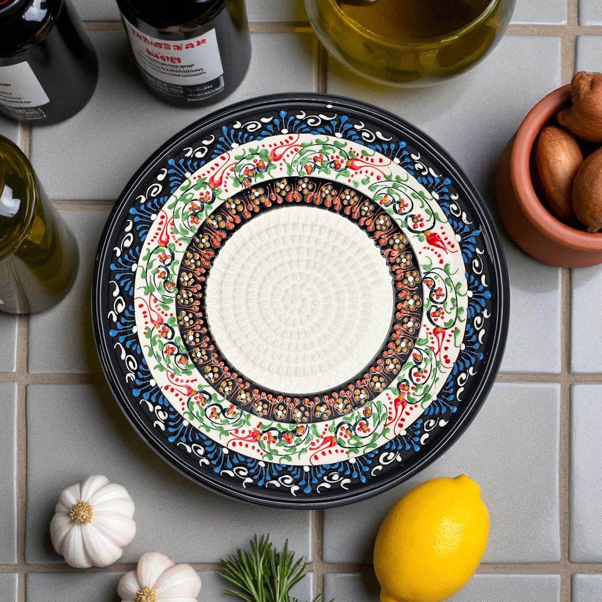 Decorative ceramic garlic grater bowl with intricate patterns on a tiled surface with ingredients.