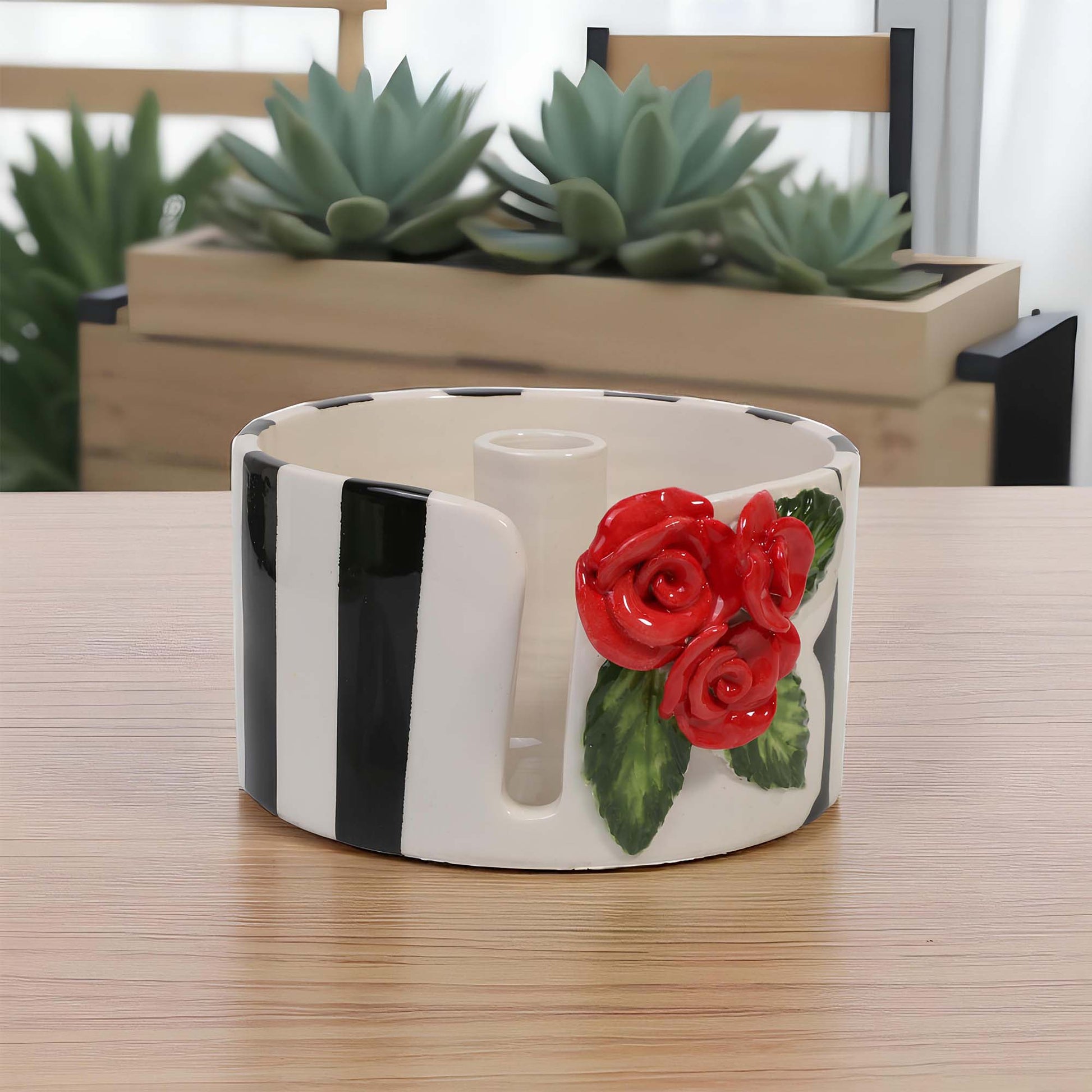 Decorative ceramic paper towel holder with red roses on a wooden surface