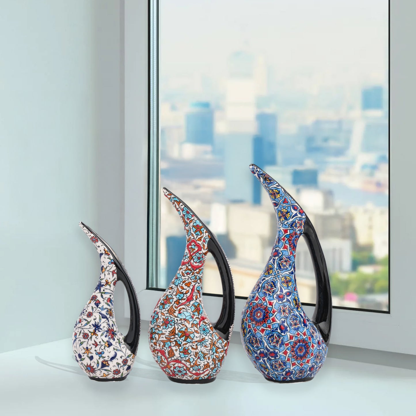 Set of 3 hand-painted ceramic ewers with Ottoman floral motifs in unique color palettes. Glossy artisan pieces with black handles, perfect décor or gifts.