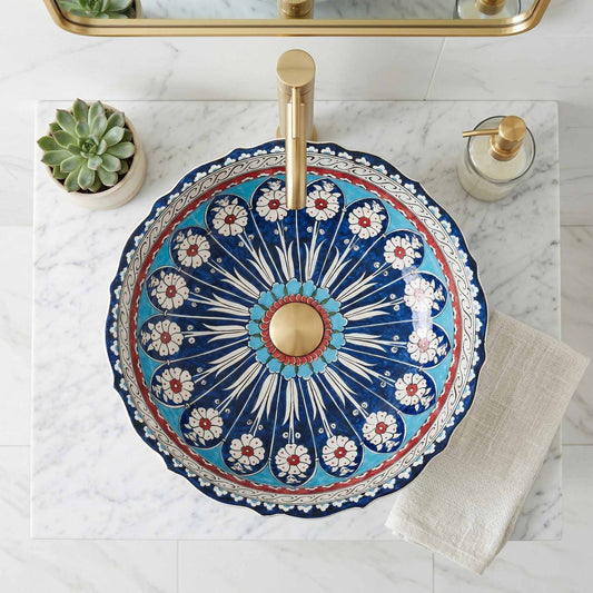 Decorative ceramic sink with floral pattern and gold faucet on marble countertop