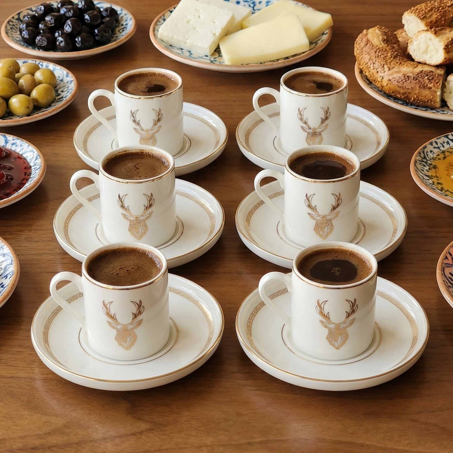 Café con leche cups with saucers on a wooden table with snacks.