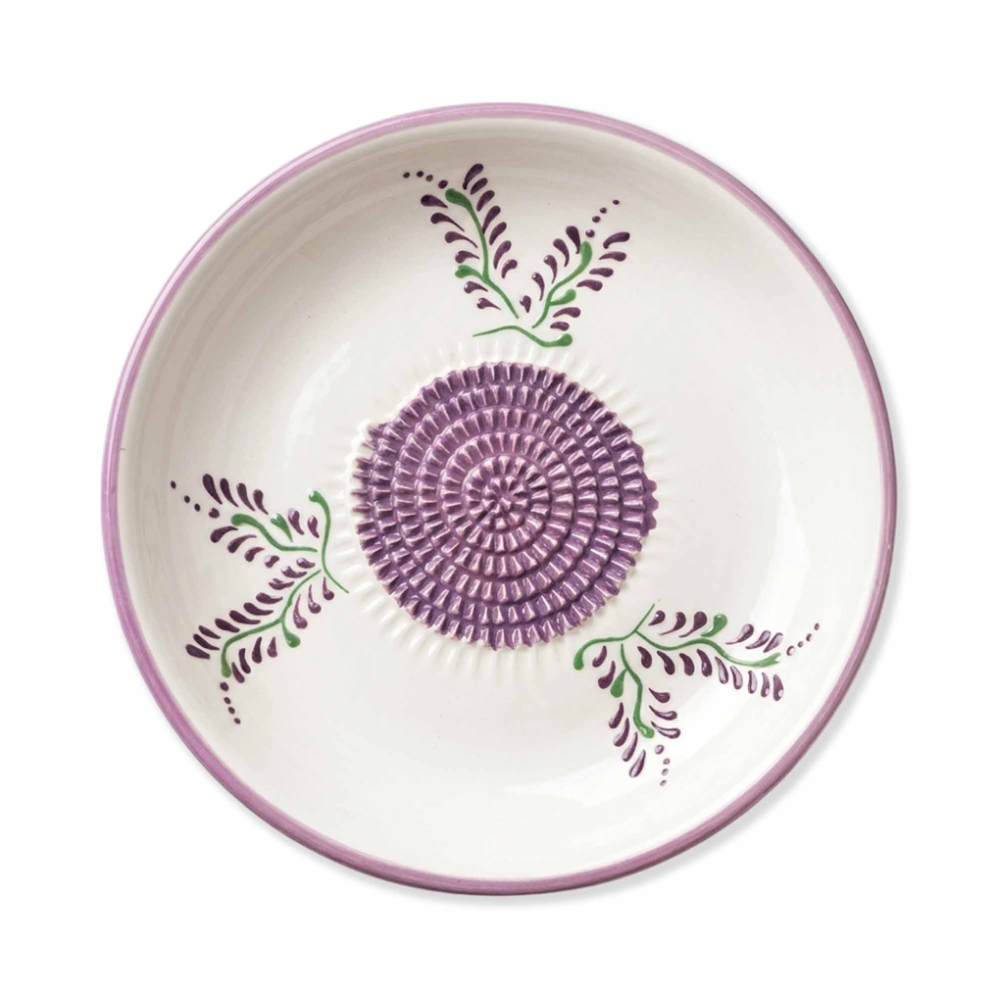 Ceramic gralic grater bowl with purple floral design on a white background