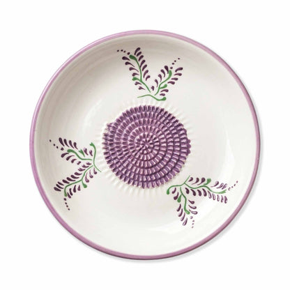 Ceramic gralic grater bowl with purple floral design on a white background