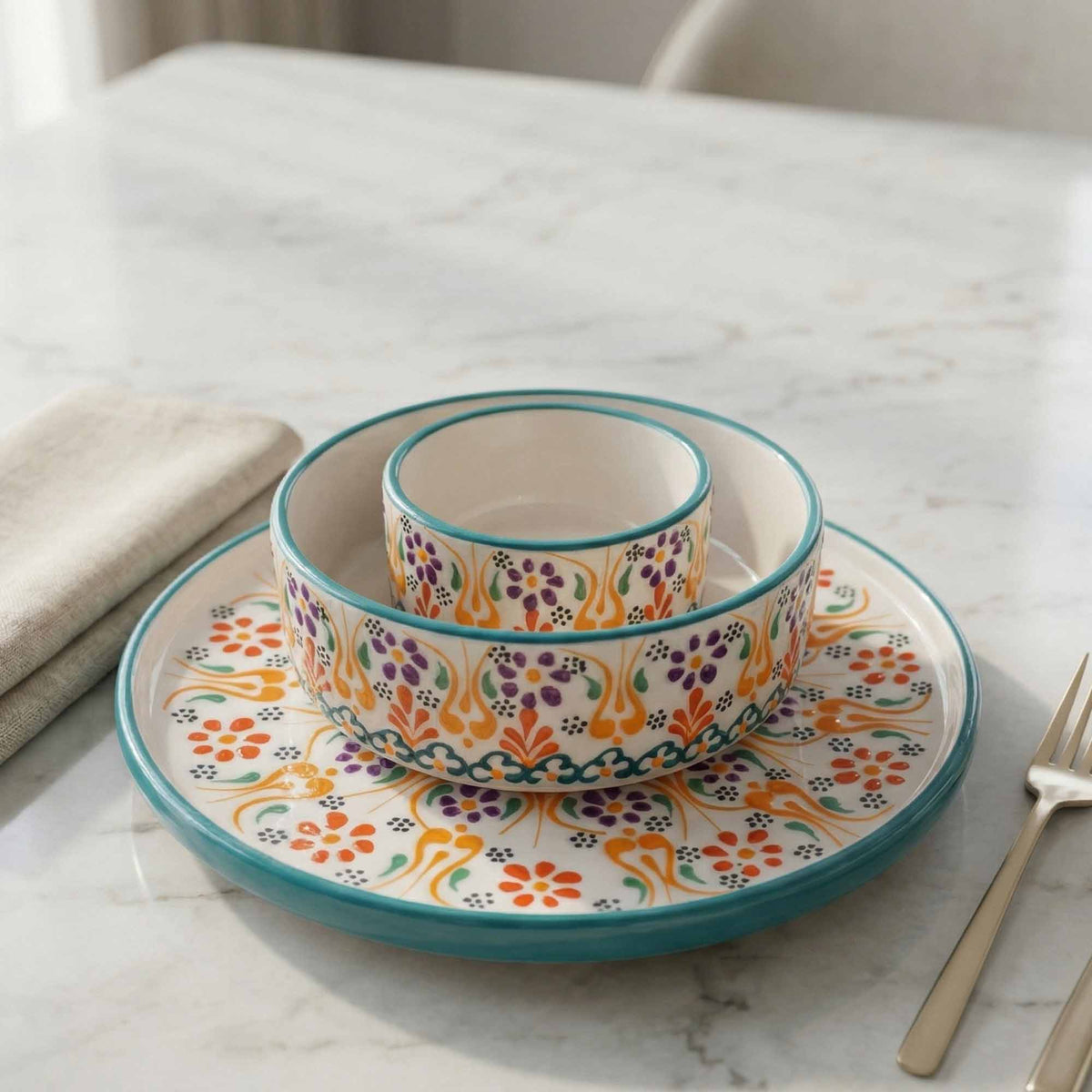 Colorful ceramic bowls and plate set on a marble surface with a fork.