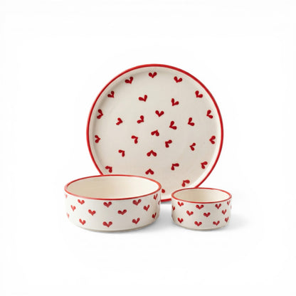 Ceramic dinnerware set with red heart patterns on a white background