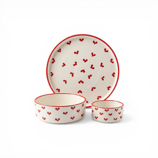 Ceramic dinnerware set with red heart patterns on a white background