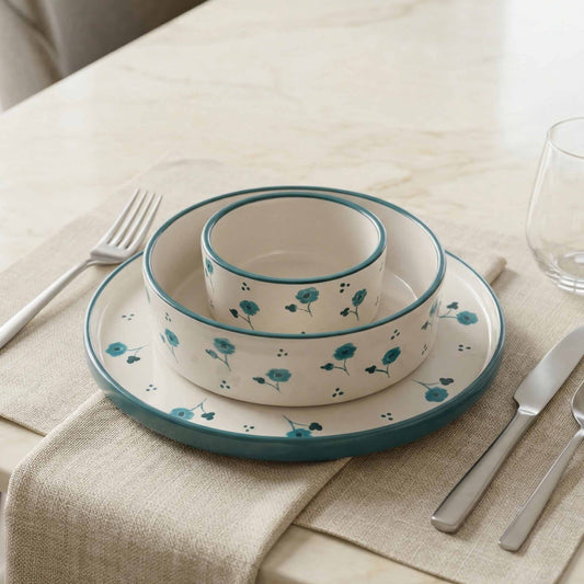 Ceramic dinnerware set with floral pattern on a table with cutlery and glass.