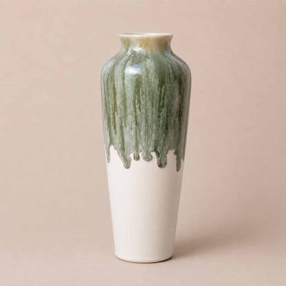 Ceramic vase with green and white glaze on a beige background