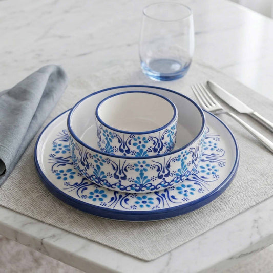 Set of blue and white ceramic dishes on a table with a glass and fork.