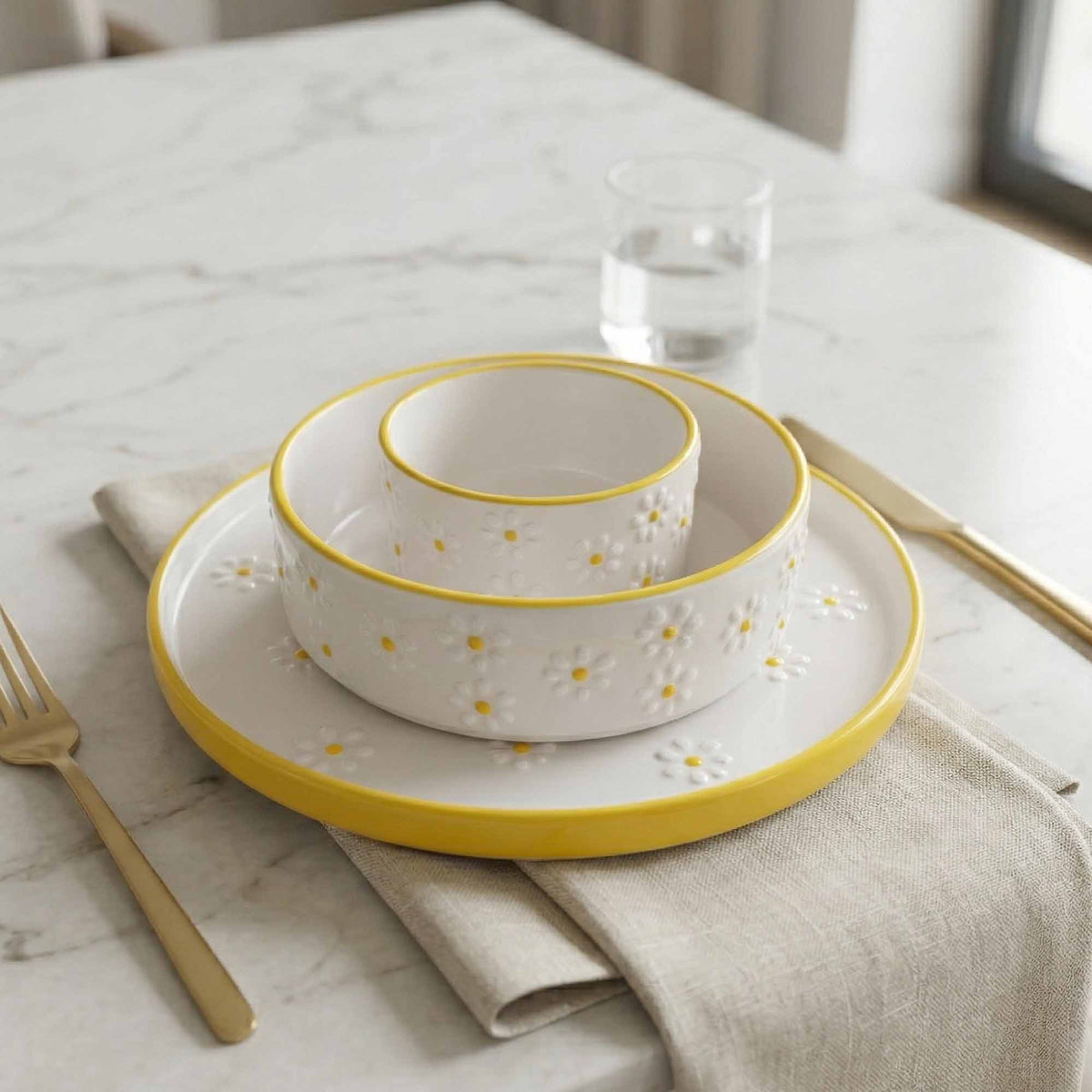 Set of white ceramic bowls with yellow rims on a marble table.