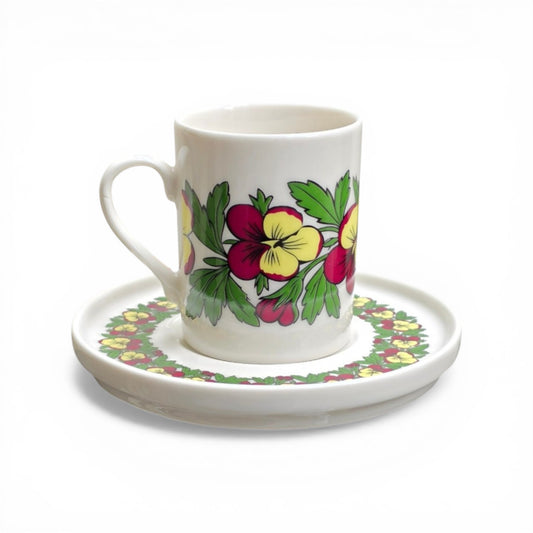 Porcelain mug and saucer with floral design on a white background