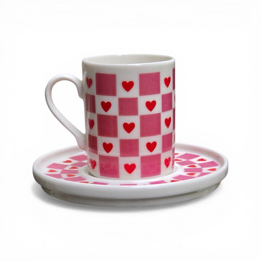 Porcelain cup and saucer with red heart pattern on a white background