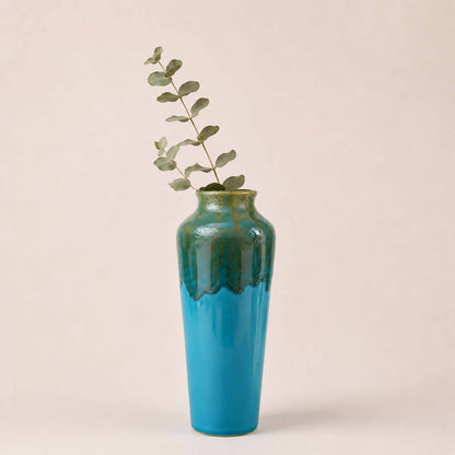 Blue ceramic vase with green accents on a beige background