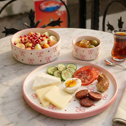 Breakfast setting with a plate of food, bowls of fruit and honey, and a glass of tea on a marble table.