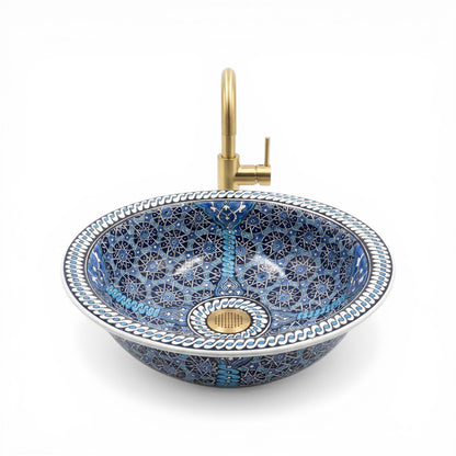 Decorative blue mosaic ceramic sink with a gold faucet on a white background