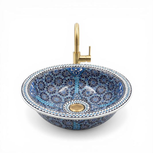 Decorative blue mosaic ceramic sink with a gold faucet on a white background