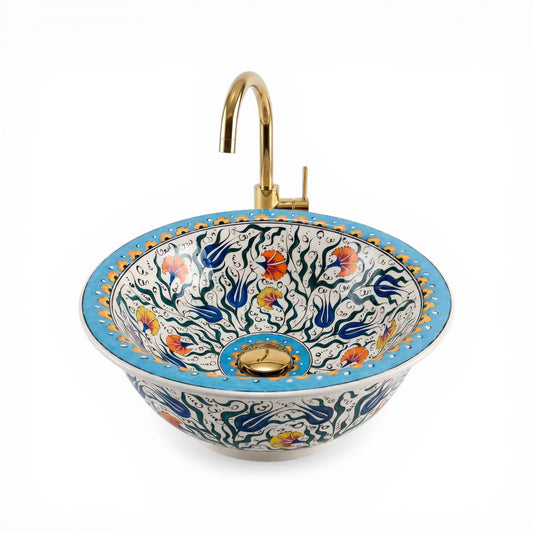 Decorative ceramic sink with floral patterns and a gold faucet on a white background