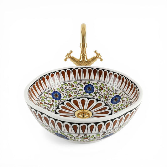 Decorative ceramic sink with floral patterns and a gold faucet on a white background