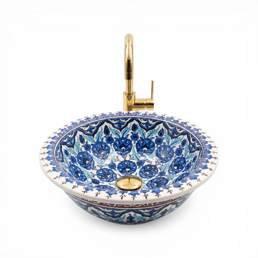 Decorative ceramic sink with blue floral patterns and gold fixtures on a white background