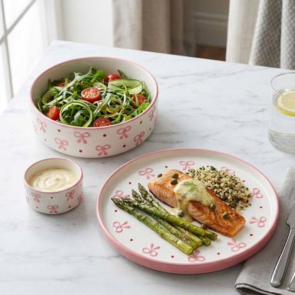 Dinner setting with salmon, asparagus, and salad on a decorative plate with a pink rim.