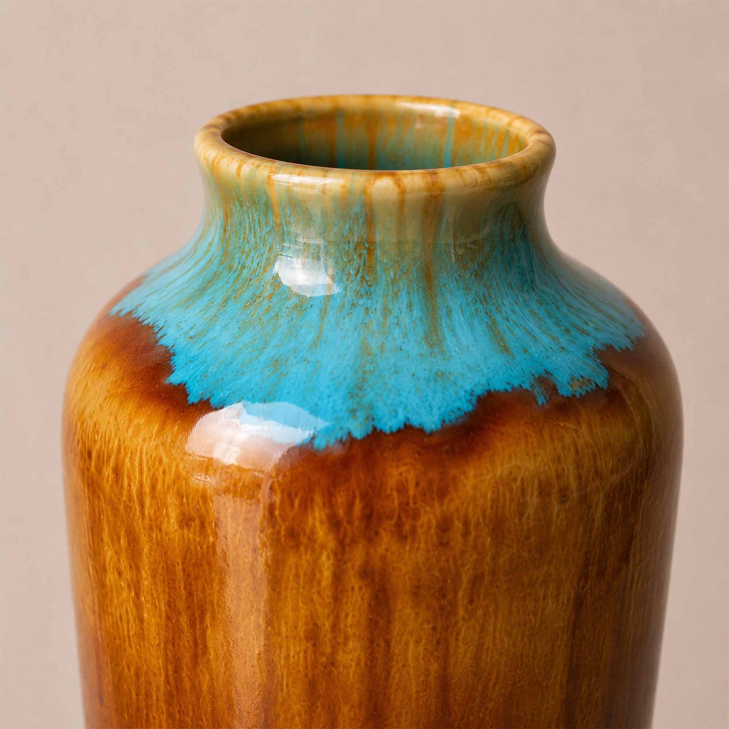 Ceramic vase with brown and blue glaze on a beige background