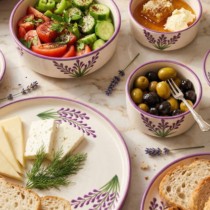 Assorted food items including a salad, olives, cheese, and bread on a marble surface with decorative elements.