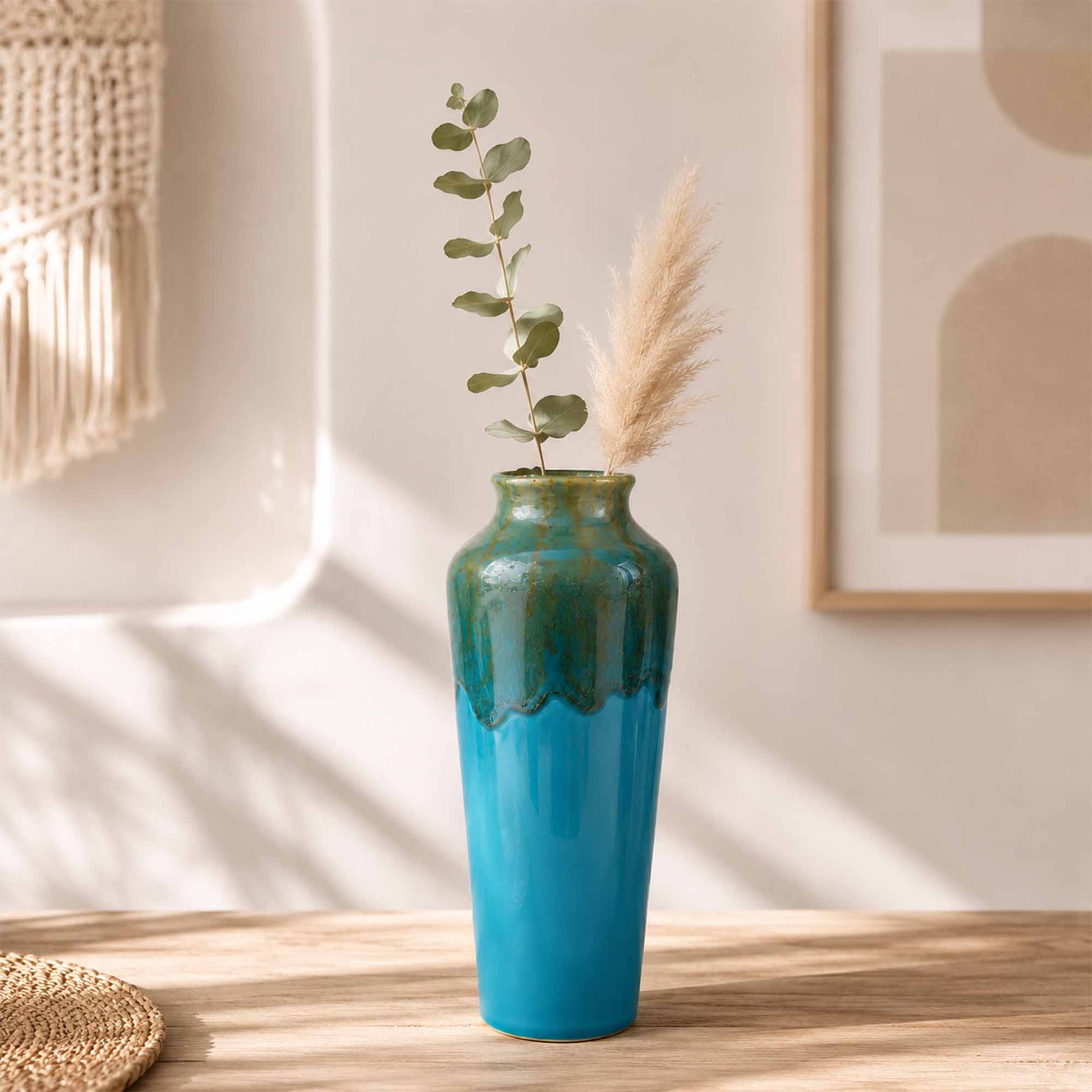 Blue and green ceramic vase with plants on a wooden table
