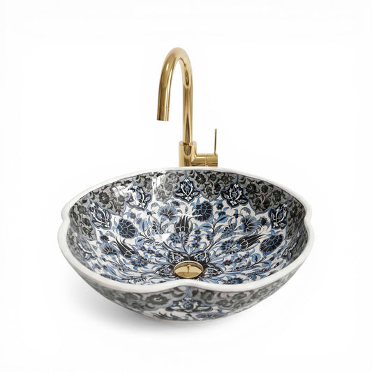 Decorative floral-patterned ceramic sink with a gold faucet on a white background