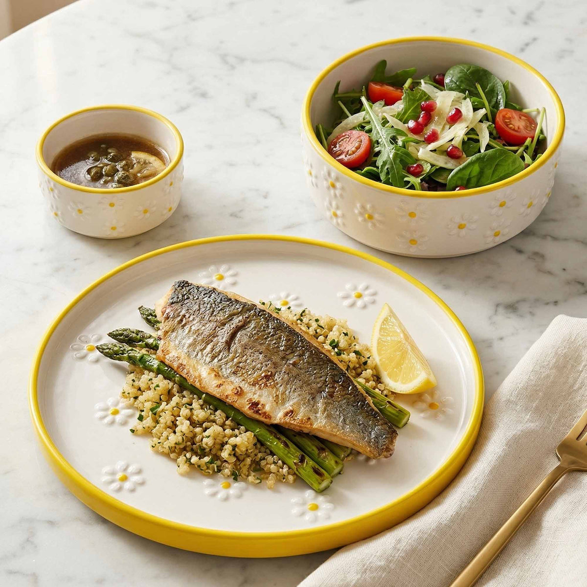 Plated dish of fish and asparagus with a side salad on a marble table.