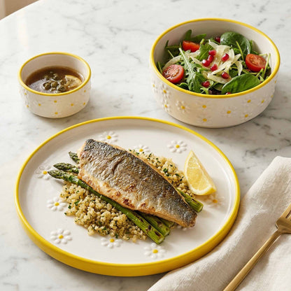 Plated dish of fish and asparagus with a side salad on a marble table.