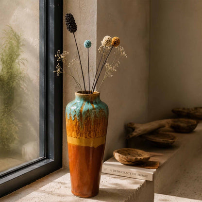 Decorative ceramic vase with dried flowers on a windowsill
