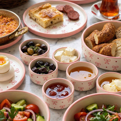 Assorted food items on a marble surface with pink decorative plates and bowls.