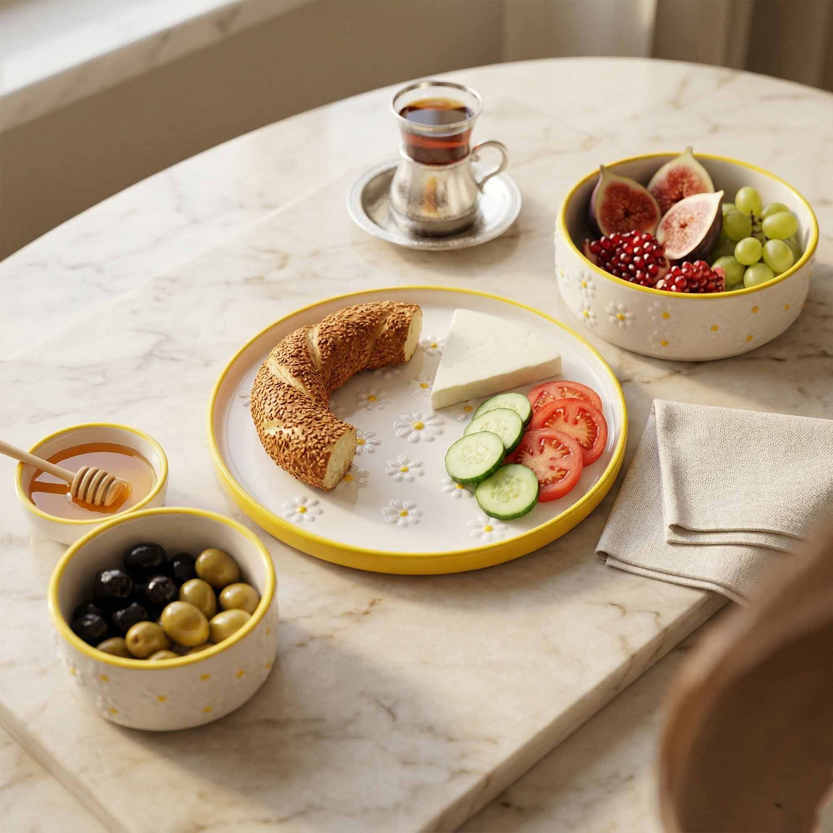 Breakfast setting with croissant, cheese, fruits, and tea on a marble table.